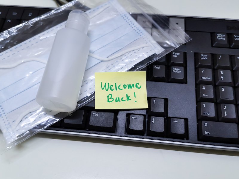 Welcome Back Note With Hand Sanitizer And Mask On Top Of Keyboard