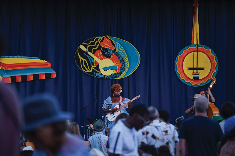 Woman on stage with a guitar, singing into mic