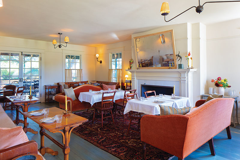 The interior of Mosquito Supper Club featuring lounge couches, clothed tables, wooden dining chairs, and lots of natural sunlight