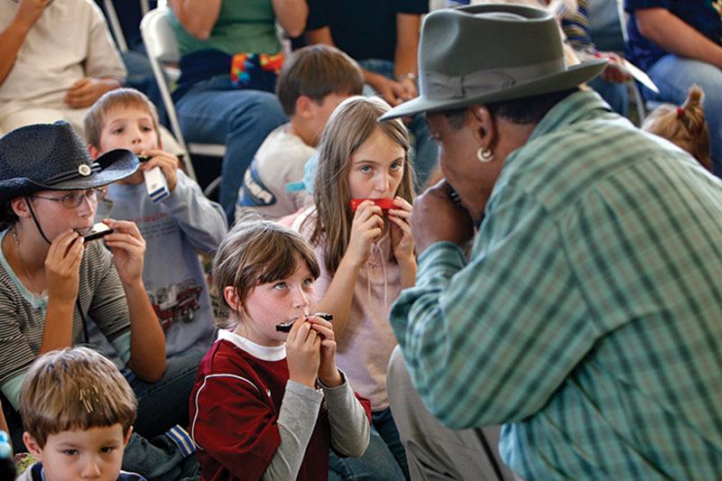 Man teaching children how to use a harmonica