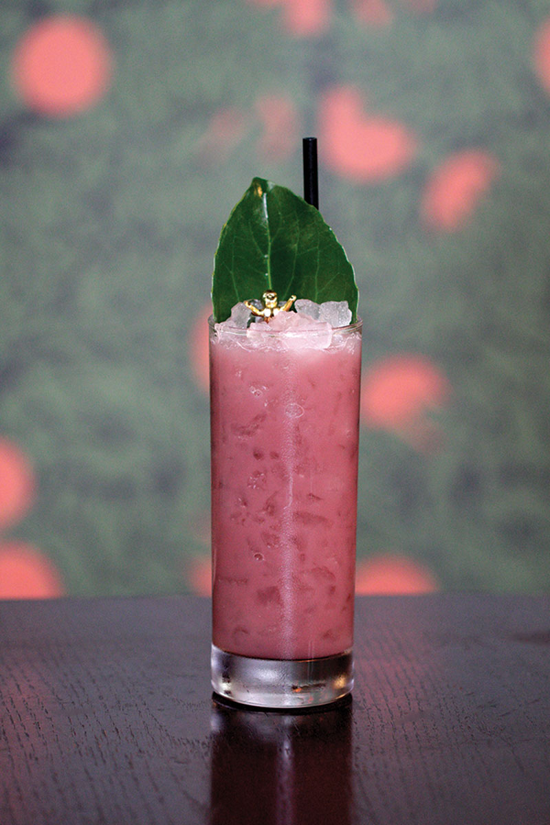 Bar Tab: Carnival Menus, THC-infused Seltzers and More The Carnival Colada (pink opaque mixed drink in a tall glass, with a big leaf and gold kingcake baby as garnish)