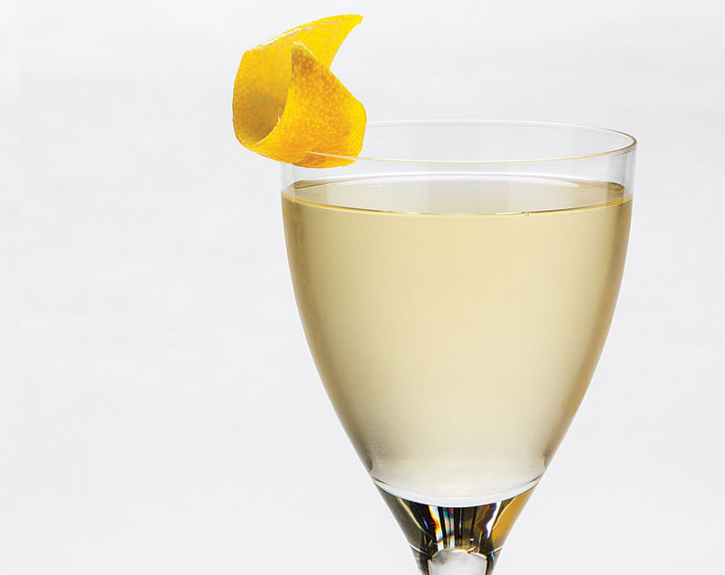 Fives Bar Elixir of Life -- a pale yellow drink in a small stemmed glass with a lemon twist on the rim.